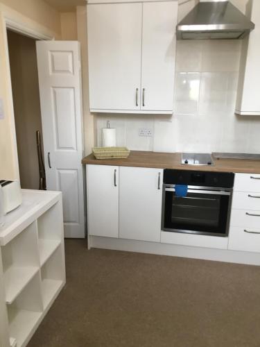 a kitchen with white cabinets and a black oven at Milton Lodge in Weston-super-Mare