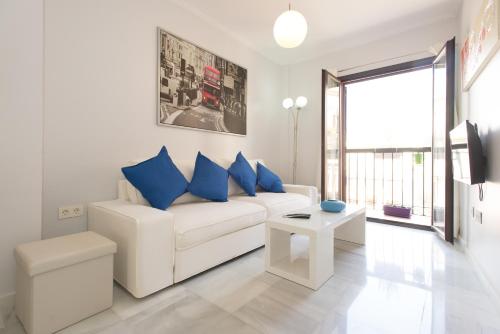 a living room with a white couch and blue pillows at The Zentral Suites & Apartments in Seville