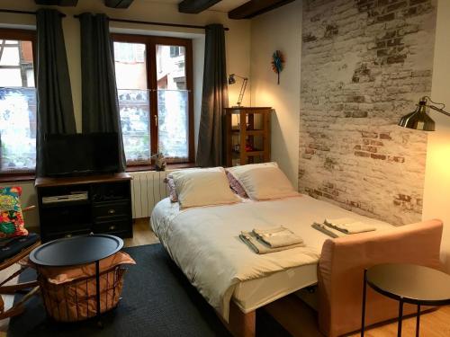 Schlafzimmer mit einem Bett, einem TV und einer Ziegelwand in der Unterkunft l’Atelier in Sélestat