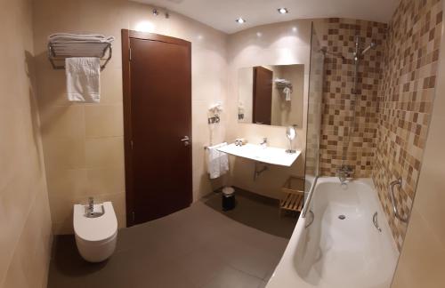 a bathroom with a tub and a toilet and a sink at Hotel Pago del Olivo in Simancas