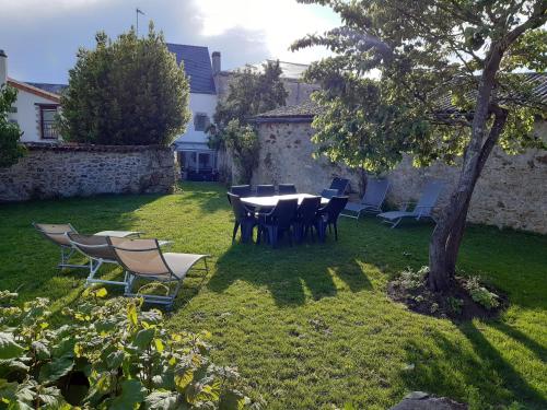 una mesa y sillas en un patio con un árbol en GITE IZALIN AVEC SPA A 20 min du Puy du Fou en Mauléon