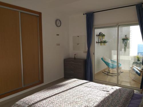 1 dormitorio con 1 cama y ventana con silla en La belle vue, en Asilah