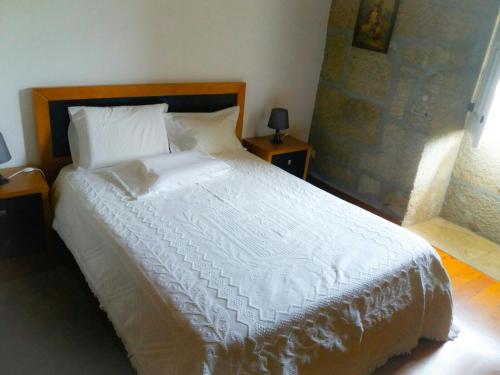 a bedroom with a large bed with white sheets and pillows at Casa de Campo Cabriz Casa do Brasileiro in Vila Real