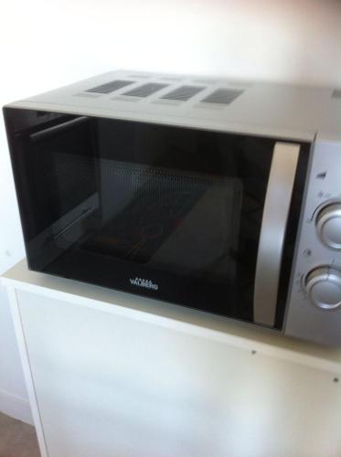 Un four micro-ondes est installé au-dessus d'une armoire. dans l'établissement Au coeur de bourg..., à Saint-Lunaire