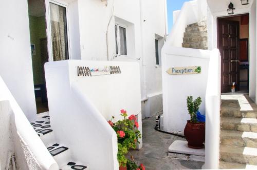 a stairway with white walls and flowers in a house at Christina Rooms in Adamas