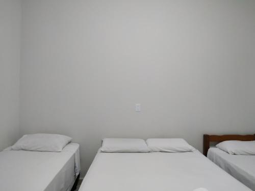 two beds in a room with white walls at Pousada Facincani in Olímpia