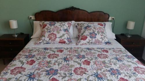 1 cama con colcha floral y almohadas en Cal Torroner, en Tremp