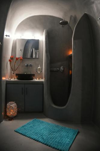 a bathroom with a sink and a mirror and a rug at Serenity Blue (Cave house) in Akrotiri