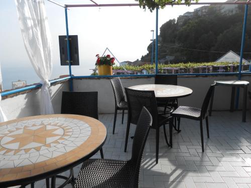 a patio with tables and chairs on a balcony at Al Geranio B&B in Furore