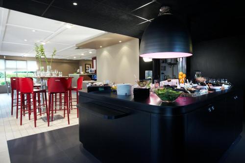 une cuisine avec un comptoir noir et des chaises rouges dans l'établissement Campanile Grenoble Nord - Saint-Egrève, à Saint-Égrève