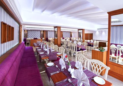 ein Restaurant mit Tischen und Stühlen und einer lila Couch in der Unterkunft Hotel Abad Plaza in Kochi