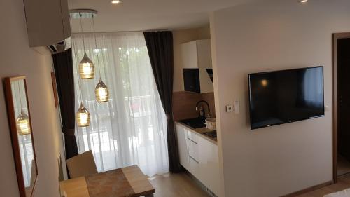 a living room with a television and a kitchen at Tündérlak Vendégház in Balatonfüred