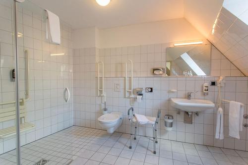 a bathroom with a toilet and a sink and a mirror at Hotel Restaurant Brintrup in Münster