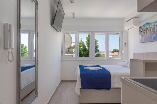 a bedroom with a bed and a sink and windows at Casteletti in Kaštela