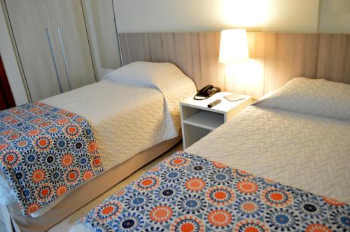 a hotel room with two beds and a table with a phone at Catussaba Suítes Resort in Salvador