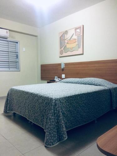 a bedroom with a bed with a blue comforter at Primavera Palace Hotel in Nova Andradina