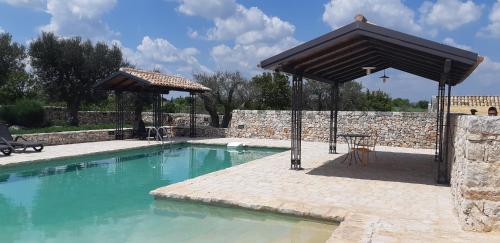 a swimming pool with a pavilion next to a stone wall at Dimora Mastromarco in Noci
