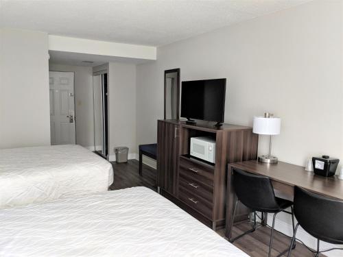 a hotel room with a desk with a television and a bed at Lakefront Terrace Resort in Lake George