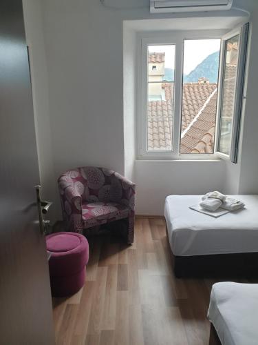 a room with a bed and a chair and a window at Nova dvokrevetna soba sa dva odvojena kreveta i zajedničkim kupatilom in Kotor