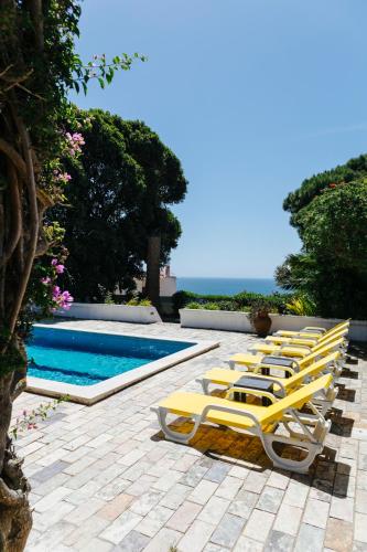 a row of yellow lounge chairs next to a swimming pool at Great view to sea, villa with pool in Salema