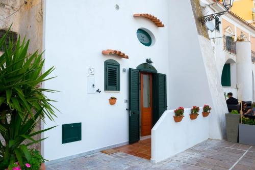 a white building with a black door and potted plants at MARINELLA CASA VACANZE in Cetara