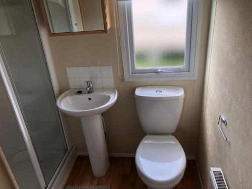 a bathroom with a toilet and a sink and a window at 4 bedroom 10 berth caravans with Hot Tub ,Mountain Bikes Tattershall Lakes in Tattershall