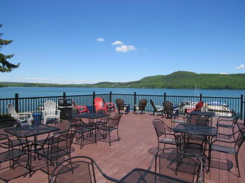 a group of tables and chairs on a deck next to the water at Lake 'N Pines Motel in Cooperstown