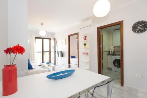 a white table with a red vase on top of it at The Zentral Suites & Apartments in Seville