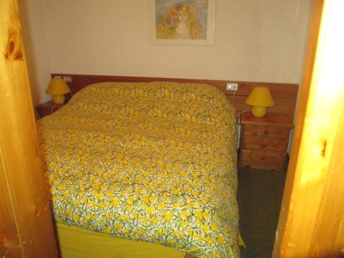 Bilocale con box - Condominio Cardinello Rosa في ماديسيمو: غرفة نوم بسرير ولحاف اصفر ومصباحين