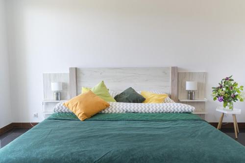 a large bed with green sheets and yellow pillows at Nowa Dana Ośrodek Wypoczynkowy in Łebcz