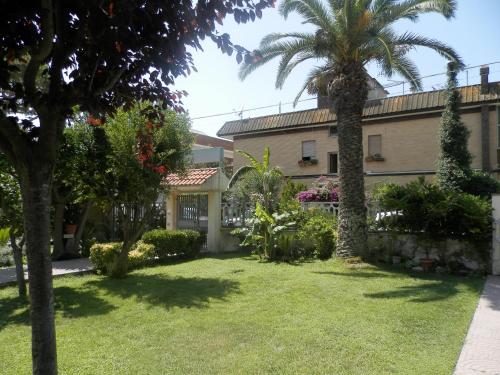 a garden in front of a building with a palm tree at Luana Inn Holiday in Fiumicino