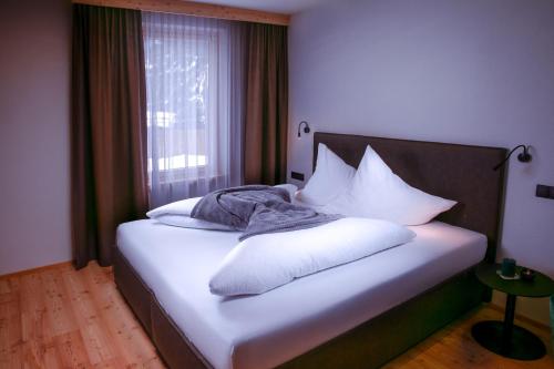 Un dormitorio con una cama con almohadas blancas y una ventana en Alpinlodge Ladis en Ladis