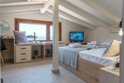 a bedroom with a bed and a tv and a window at Cavas Luxury Apartments in Iraklitsa