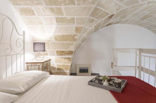 a bedroom with a white bed and a stone wall at Kate in Leverano