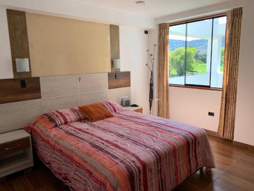 1 dormitorio con cama y ventana grande en Mviajes Travel & Services, en Cajamarca