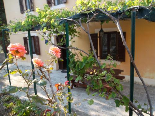 a pergola with flowers in front of a house at Hodak Apartment in Nerezine