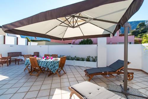 a patio with a table and chairs and an umbrella at Near The Port Apartment in Cala Gonone