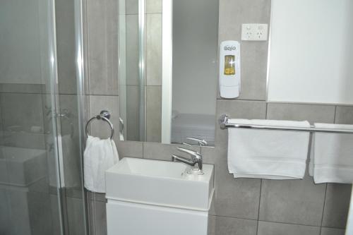 a bathroom with a sink and a shower with towels at Garden Hotel in Dubbo