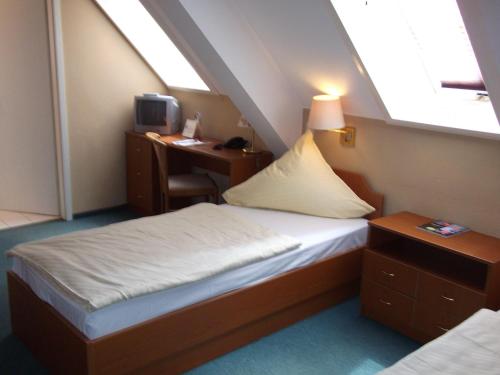 a small room with a bed and a desk with a computer at Pension & Café Am Krähenberg in Halle an der Saale