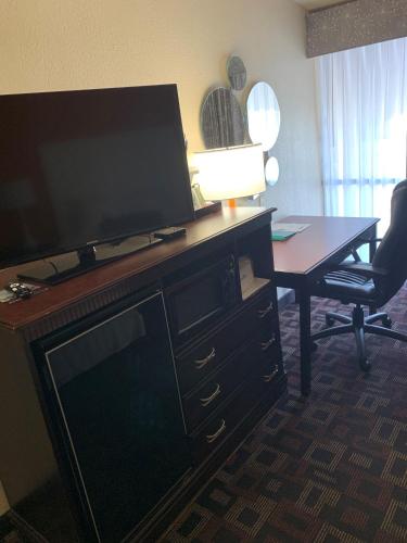 a living room with a flat screen tv and a desk at Howard Johnson by Wyndham Oklahoma City OKC Airport, Fairgrounds, I40 in Oklahoma City