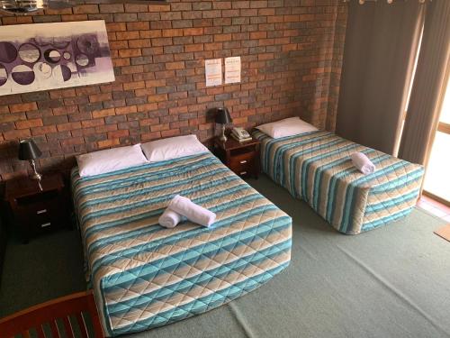 two beds in a room with towels on them at Bridge Street Motor Inn in Toowoomba