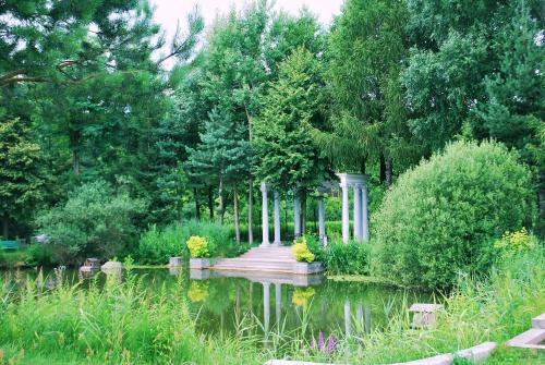 a garden with a wooden bridge over a pond at Hotel Książę Poniatowski in Lesznowola