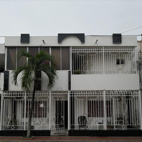 un edificio blanco con puertas y una palmera en Hospedaje el Parque, en Soledad