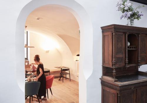 a woman sitting at a table in a kitchen and a large wooden cabinet at Faktorei in Innsbruck