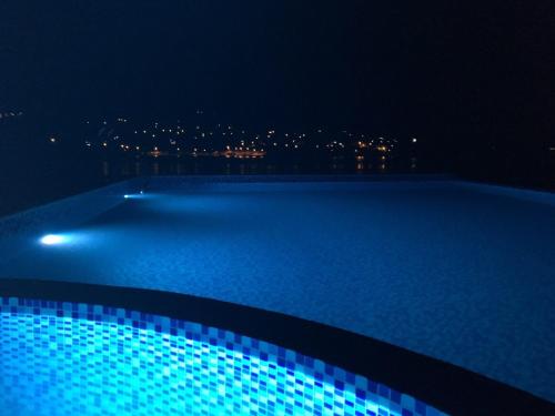 a swimming pool at night with a city in the background at Apartments Komina in Utjeha