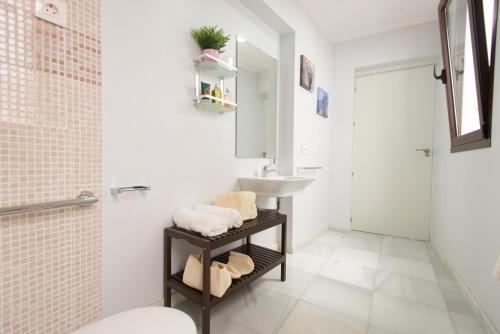 a white bathroom with a sink and a mirror at The Zentral Suites & Apartments in Seville