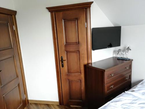 a bedroom with a bed and a dresser with a television at Villa Watamu in Trzęsacz