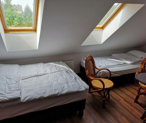 1 Schlafzimmer mit 2 Betten, 2 Stühlen und Fenstern in der Unterkunft Villa Watamu in Trzęsacz