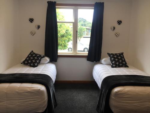 two twin beds in a room with a window at 3 & 4 Bedroom Holiday Houses Central Picton in Picton