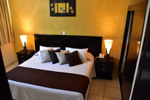 ein Schlafzimmer mit einem großen Bett mit Kissen und zwei Lampen in der Unterkunft Hotel Suite Azomali in Tula de Allende